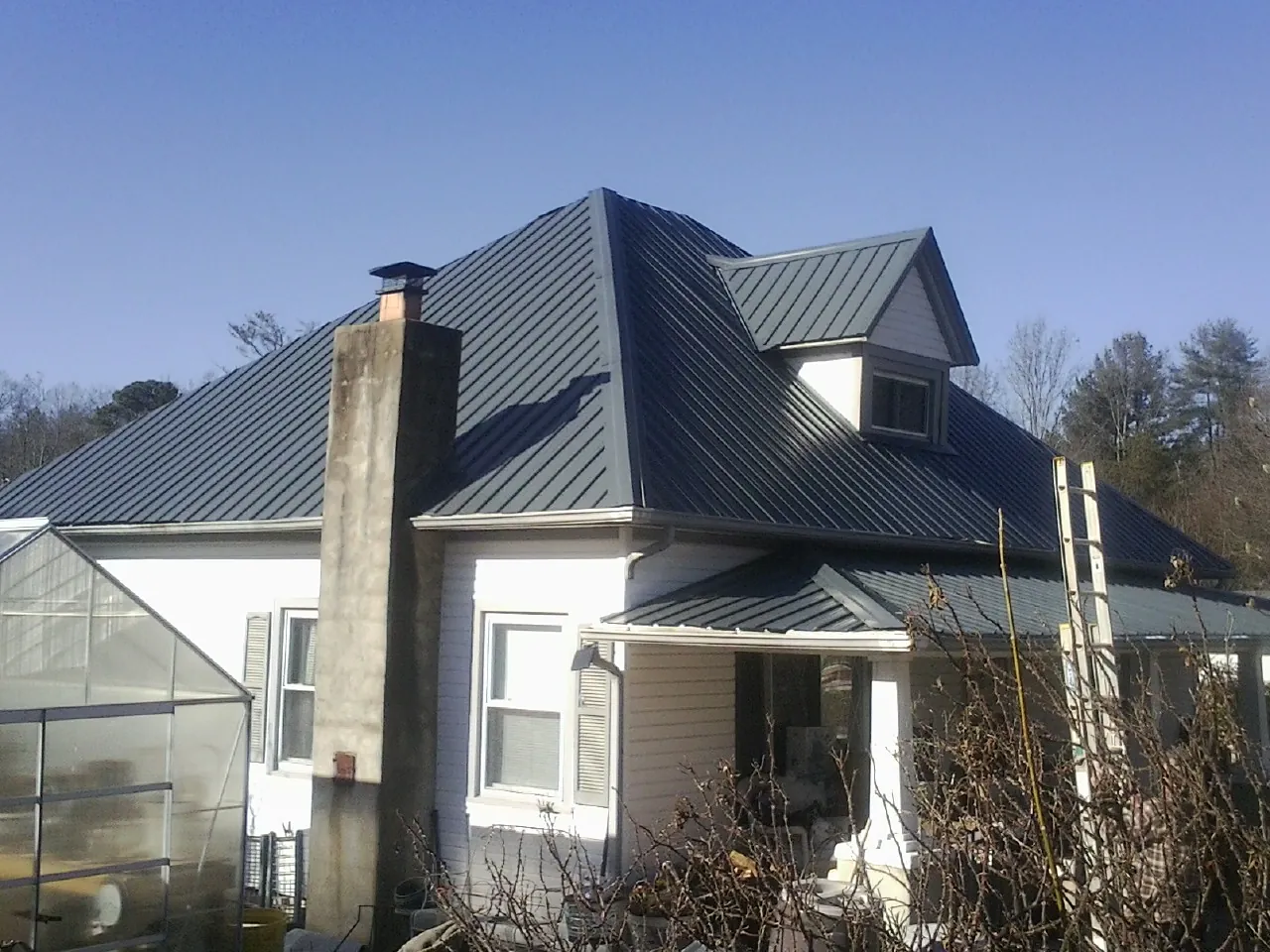 Dark blue standing seam metal roof on a white farmhouse with dormer — Slate & Tile Roof Repair by Roofing Brothers in Armuchee