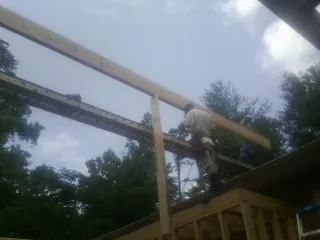 Carpenter setting a ridge beam over a new addition frame — Ice Dam Removal by Roofing Brothers in Armuchee