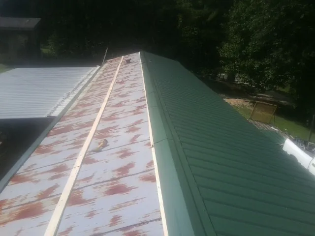 Old rusted panels beside newly installed green metal roofing — Wind Damage Roof Repair by Roofing Brothers in Armuchee