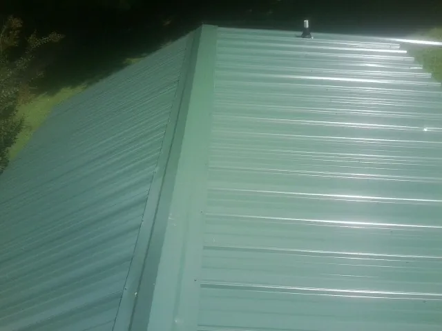 New green metal panels meeting at the ridge of a roof — Flat Roof Repair work by our crew in Armuchee