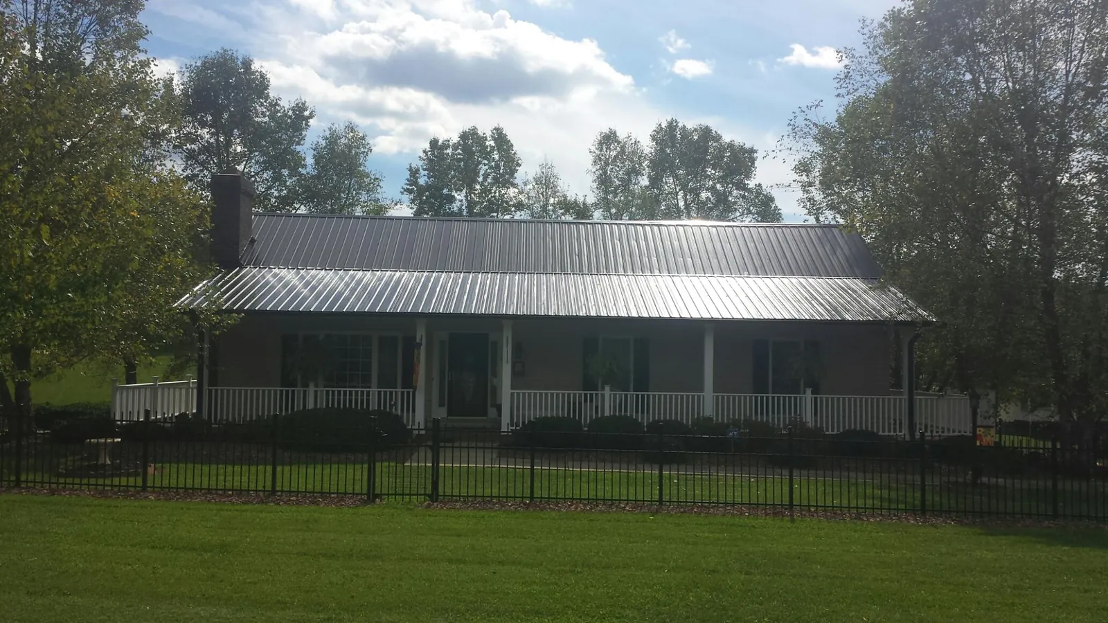 Gray metal roof on a brick ranch with a full width front porch — Gutter Guard Installation work by our crew in Armuchee