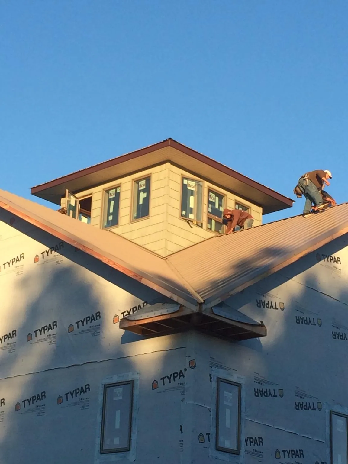 Roofers working around a rooftop cupola on a new metal roof at sunset — Roof Waterproofing in Armuchee by Roofing Brothers